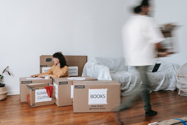 a couple packing up brown boxes to move out